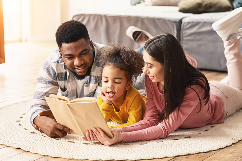 Un couple en coparentalité qui lit une histoire à une petite fille